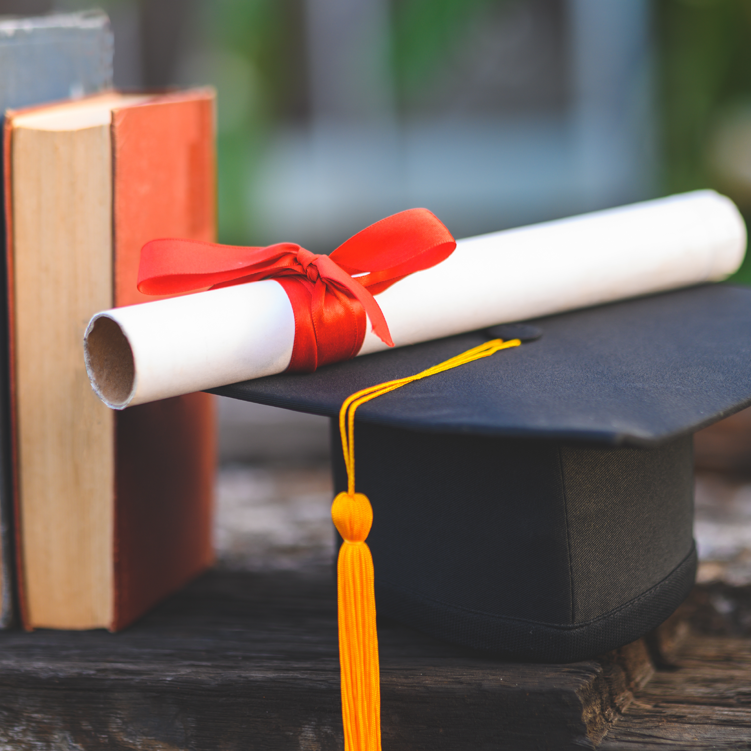 A certificate with a red ribbon tie upon a graduation cap
