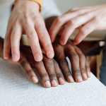 A person teaching another how to read in Braille