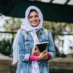 A student holding a book and smiling