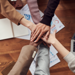 Six people with their hands in a group huddle